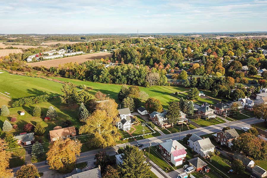 Contact - Aerial View of a Road with Homes in York Pennsylvania Surrounded by Green Trees and Grass on a Sunny Day